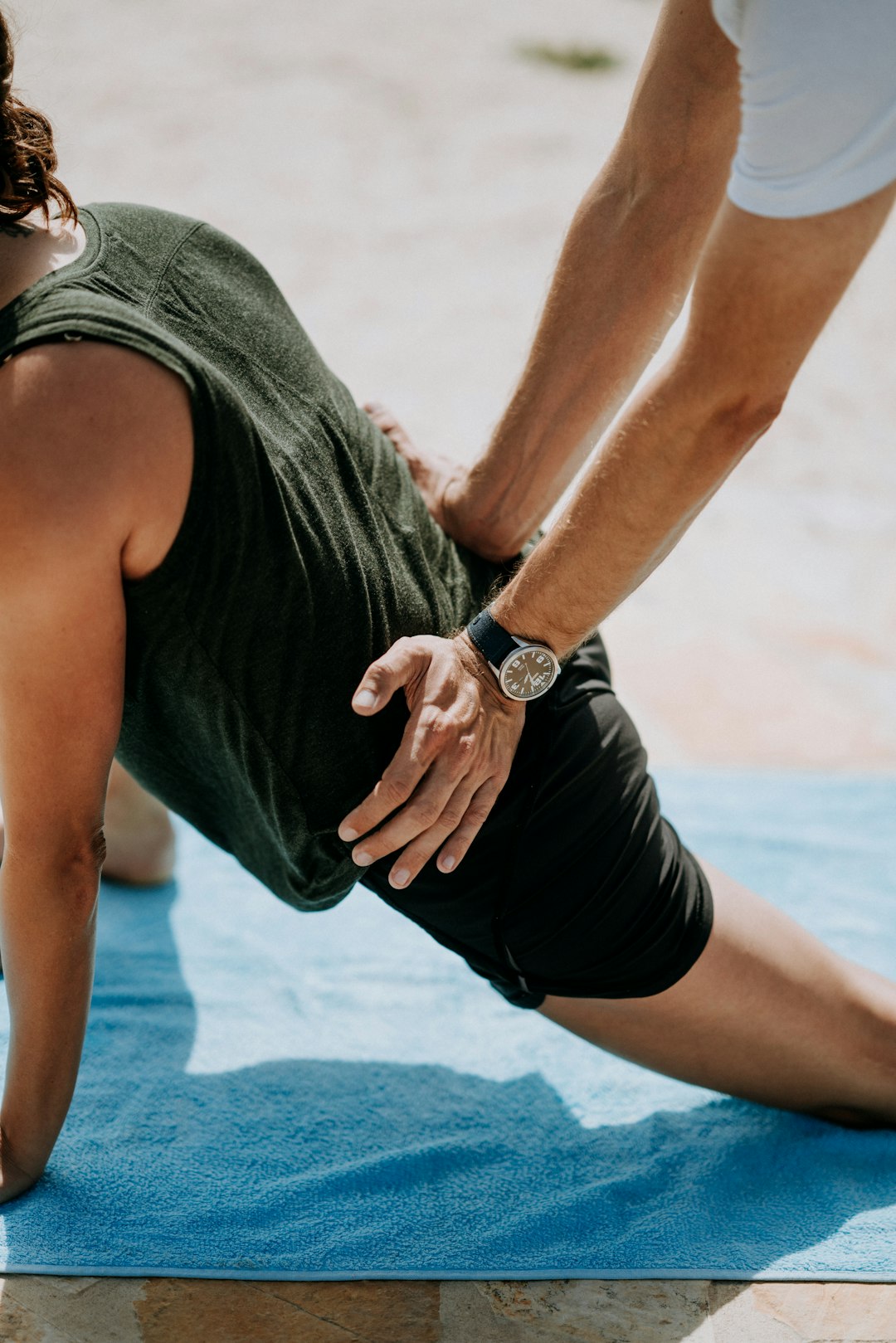 physio pressing woman back kneeling on blue towel